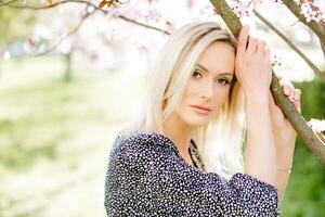 Beautiful blonde woman posing in spring blossom park photo