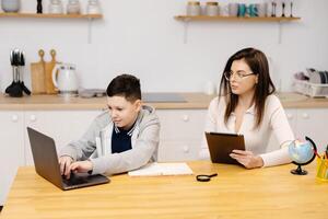 Young woman helps a boy with his lessons using a tablet and a globe. A homeschooling student does his homework with the help of a tutor. photo