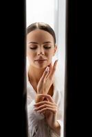 Bride hiding behind curtains looking down with closed eyes and hands near her face photo