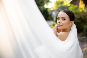 Bride posing with white veil during wedding day photo