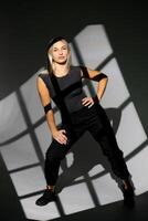 Dancer posing in studio with window light shadows, wearing black clothes photo