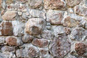 Textured stone wall made of uneven boulders in natural shades with detailed textures. photo