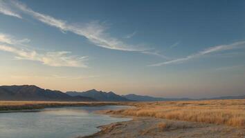 a river runs through a dry field with mountains in the background photo