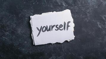 Self-concept concept on torn paper with the word yourself written on it, on a dark background photo