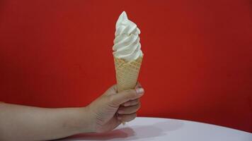 A person holding an ice cream cone with a red background photo