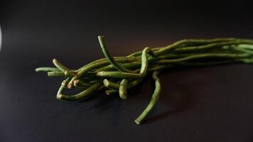 A bunch of green beans on a black surface photo