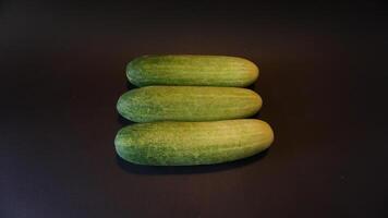 Three cucumbers are shown on a black surface photo