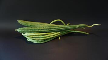 A bunch of green beans on a black surface photo