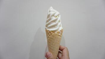 A person holding a waffle cone with whipped cream photo