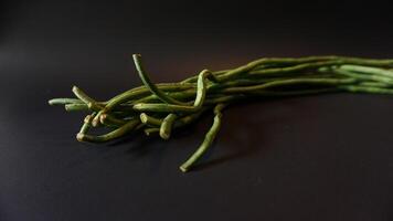 A bunch of green beans on a black surface photo
