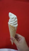 A hand holding a cone of ice cream photo