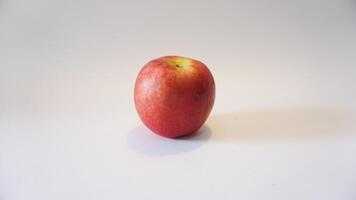 A red apple sitting on a white surface photo