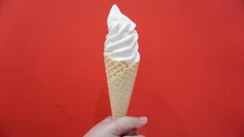 A person holding an ice cream cone with a red background photo