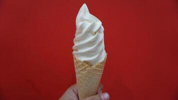 A hand holding a waffle cone with whipped cream photo