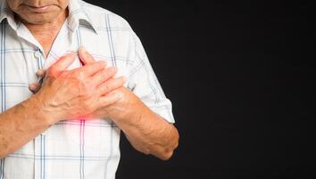 Senior man is suffering from chest pain while standing on a black background photo