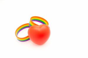 Rainbow patterned wristbands and a red heart shape symbol are on a white background photo
