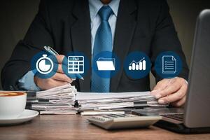 Businessman in a suit filing tax forms while sitting at the table photo