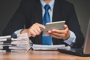 Businessman in a suit using a calculator to calculate taxes while sitting at the table photo