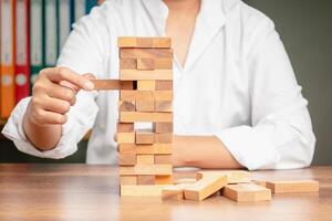 Close-up hand of a man playing a wooden block game while sitting at the table photo
