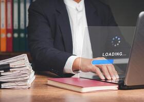Businessman uses a laptop for loading and processing data on a virtual screen. Close-up. photo