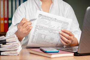Hand holding of form 1040. U.S. individual income tax return while sitting at the table in the office. Close-up. photo
