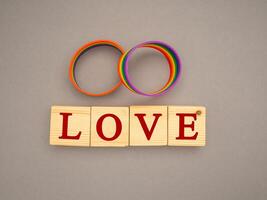 Rainbow patterned wristbands and wooden cubes with the text LOVE on a gray background photo