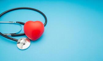 Top view of a stethoscope and a red heart shape on a blue background. photo