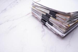 Stack of documents with binder clips on a marble table photo