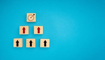 Wooden blocks with black and red arrows point to the dartboard icon on a blue background photo