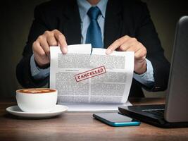 Businessman in a suit tearing up a canceled contract while sitting at the table. Close-up. photo