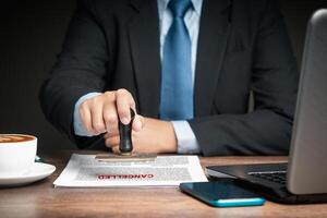 A businessman in a suit stamped for canceled documents while sitting at the table photo