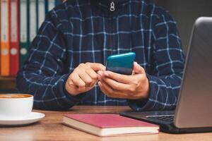 Businessman in a sweater using a smartphone while sitting at the table in the office photo