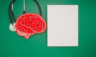 A brain shape symbol and a stethoscope and a blank white paper on a green background photo