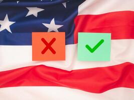 Two paper with a green checkmark and a red cross on the American flag background photo