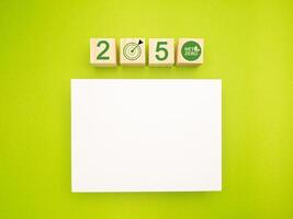 Wooden cubes with the letters 2050, graphic icons, and a blank white paper on a green background photo