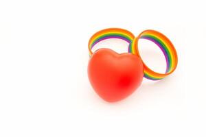 Rainbow patterned wristbands and a red heart shape symbol are on a white background. Close-up. photo