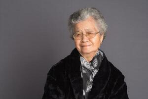 Senior woman looking at the camera while standing on a gray background photo