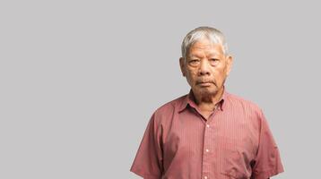 Portrait of an elderly Asian man in a shirt looking at the camera with a smile while standing on a gray background photo