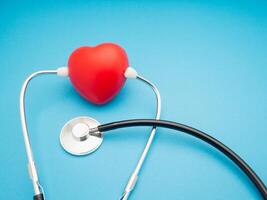Top view of a stethoscope and a red heart shape on a blue background. Close-up. photo