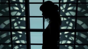 Silhouette of Woman Standing by Window with Abstract Pattern Shadows photo