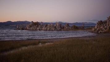 Scenic view of Mono Lake tufa formations with calm water and distant mountains at dusk. Concept of geological wonders, environmental conservation, and untouched nature. photo