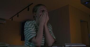 A woman is sitting at a table with her hands on her face video