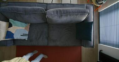 A person standing on a couch looking down at a room video