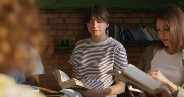 A group of people sitting around a table with books video