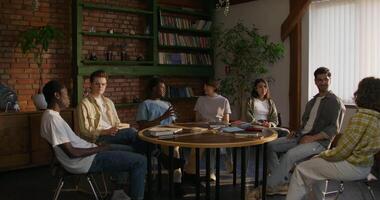 A group of people sitting around a table in a library video