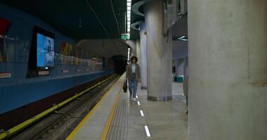 A person walking down a platform next to a train video