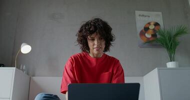 A woman sitting on a bed with a laptop video