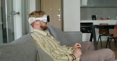 A man wearing a virtual reality headset sitting on a couch video
