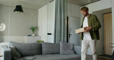 A man is standing in a room with a couch and a box video