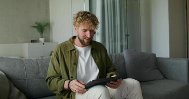 A man sitting on a couch using a tablet computer video